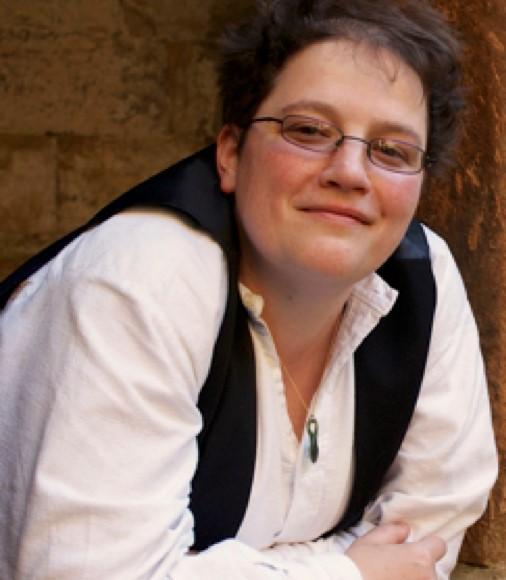 Image of Niamh NicDaied. She has short hair and glasses and is wearing a white shirt and dark waistcoat