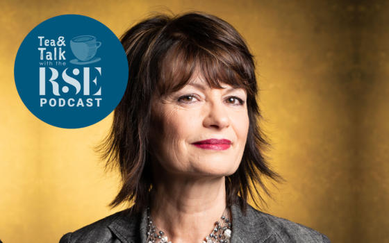 Professor Anne Glover has short, feathered dark hair and is wearing a grey jacket and necklace, against a gold coloured background. The Tea and Talk podcast logo is to the left of her face when looking at the photo straight on.