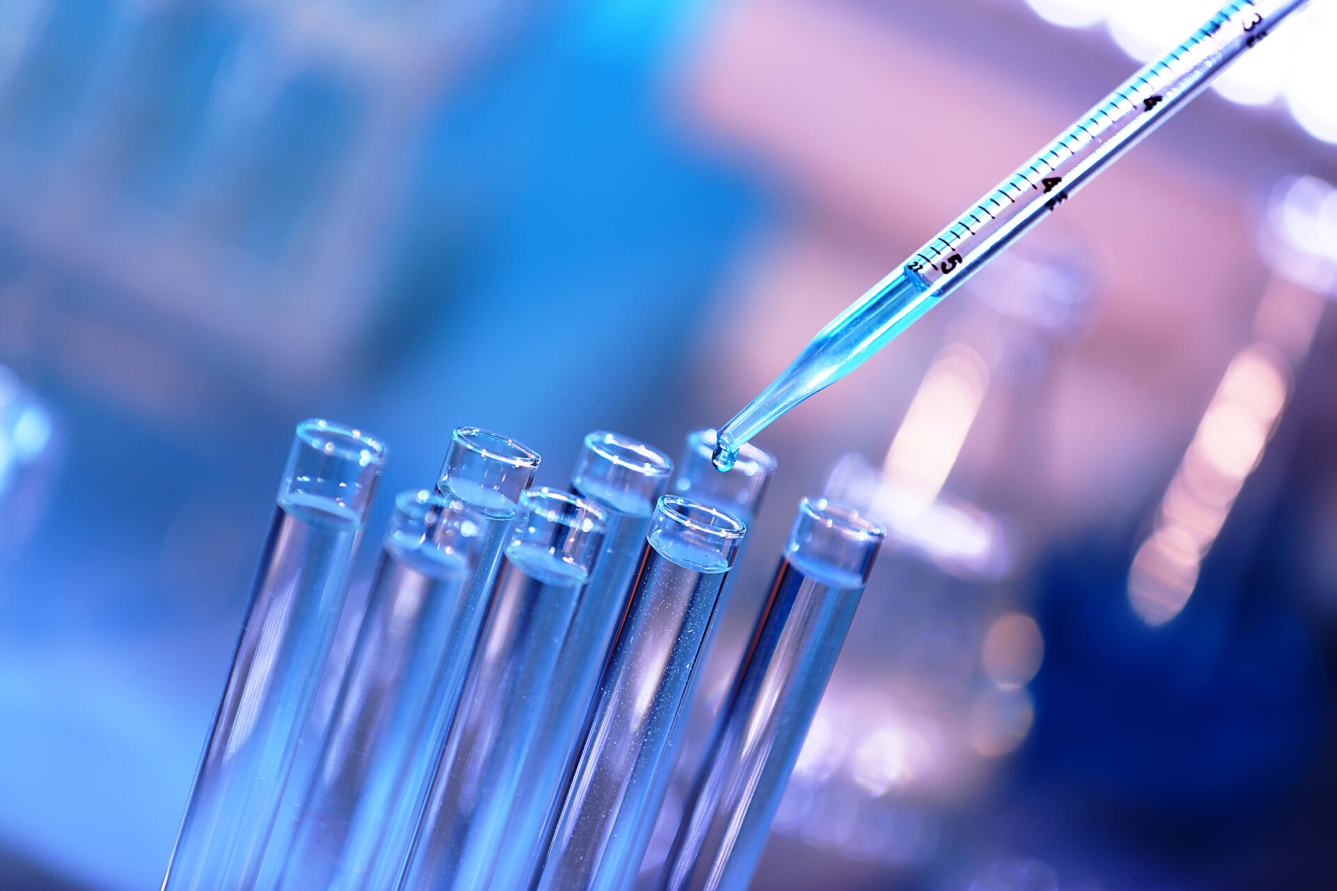 A pipette drops liquid into a test tube.