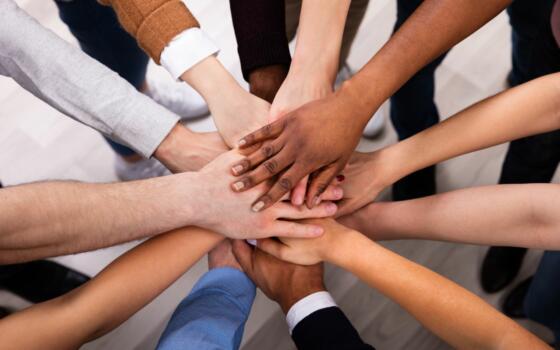 High angle view of hands stacking together in circle.