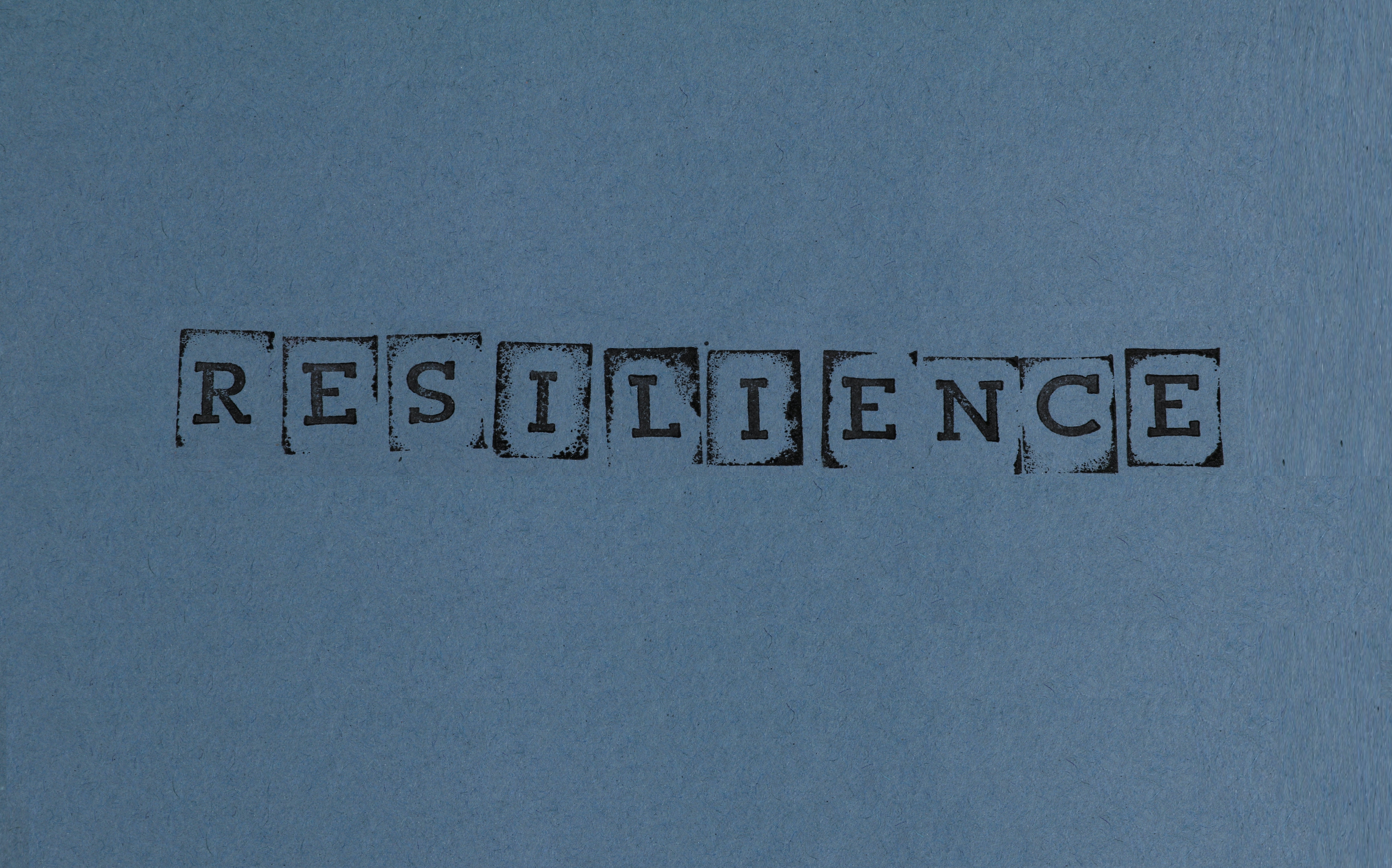 The word resilience is stamped on blue paper