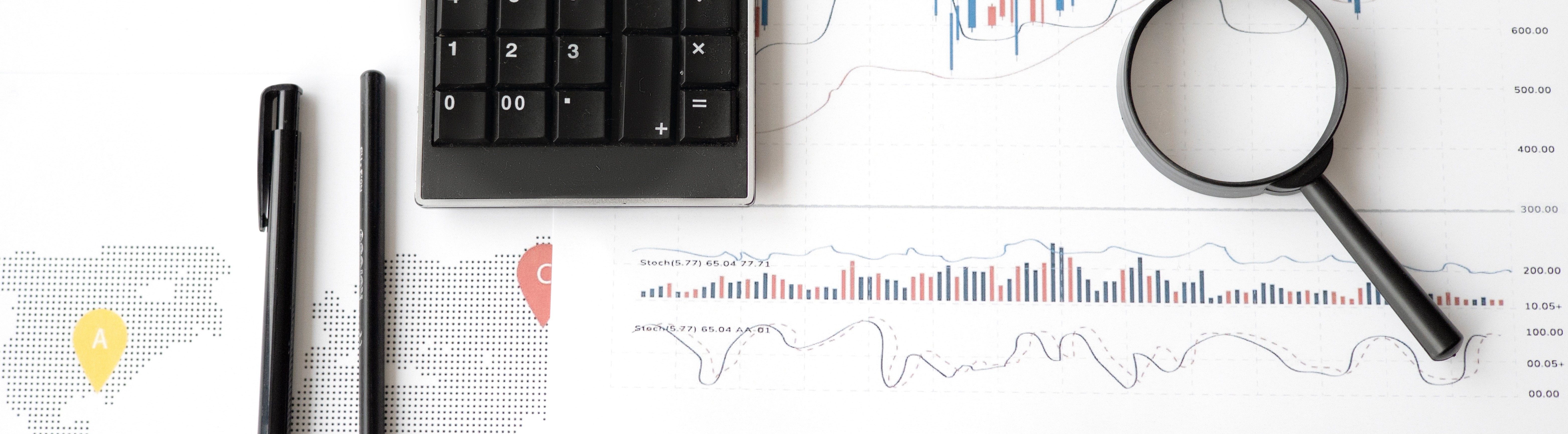 A pen and pencil rest on a map and a graph. A calculator is also visible.