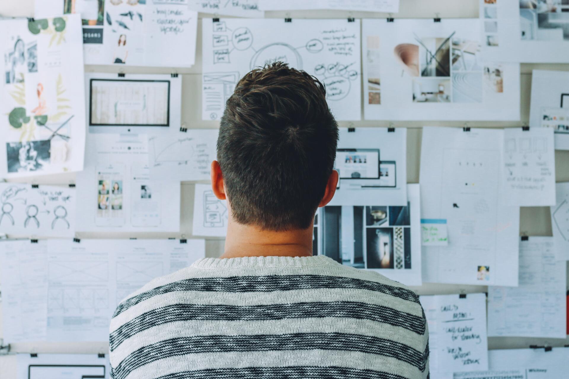 A man seen form behind looking at a wall full of planning materials.